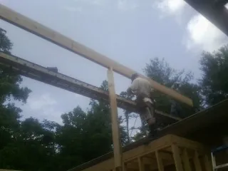 Carpenter setting a ridge beam over a new addition frame — Ice Dam Removal by Roofing Brothers in Four Lakes