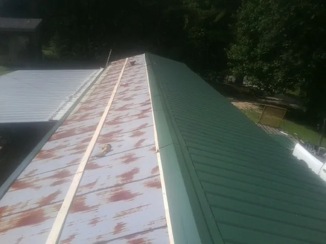 Old rusted panels beside newly installed green metal roofing — Wind Damage Roof Repair by Roofing Brothers in Four Lakes