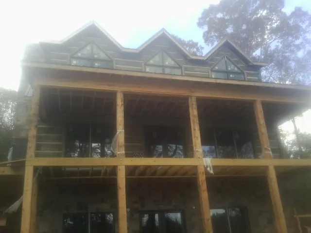 Dormers and porch framing on a large log home under construction — Roof Coating work by our crew in Four Lakes