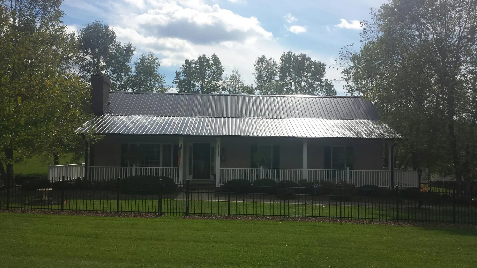 Gray metal roof on a brick ranch with a full width front porch — Gutter Guard Installation work by our crew in Four Lakes