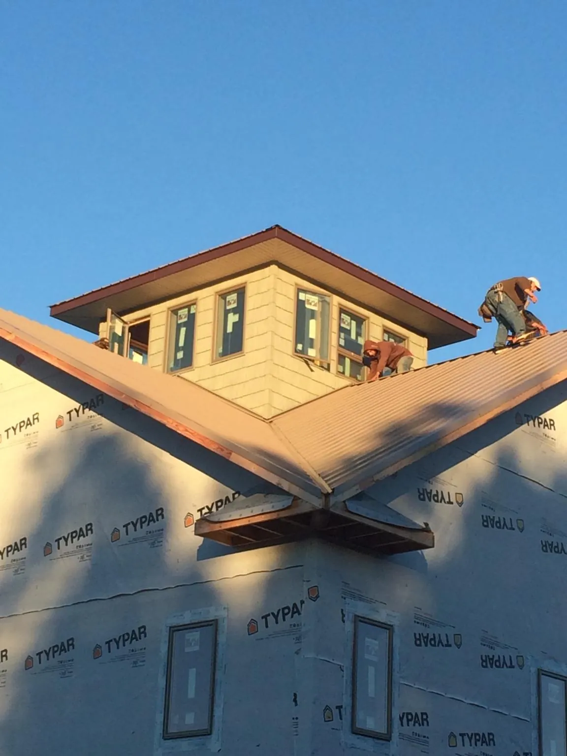 Roofers working around a rooftop cupola on a new metal roof at sunset — Roof Waterproofing in Four Lakes by Roofing Brothers